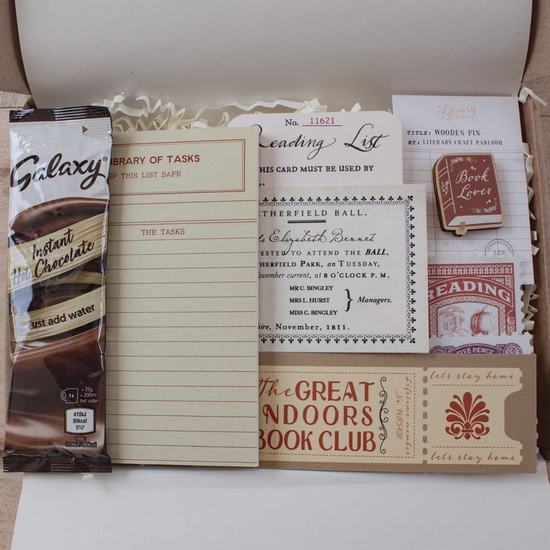 May include: A gift box containing a Galaxy instant hot chocolate packet, a cream-colored Library of Tasks notepad, a Reading List card, a Netherfield Ball invitation, a wooden book-shaped pin, a reading stamp, and a Great Indoors Book Club ticket.