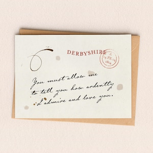 Peut inclure: Une carte de vœux crème avec du texte manuscrit et une enveloppe marron. La carte présente une citation et un tampon rouge qui dit "DERBYSHIRE A 14. FE 14 1814". Le texte sur la carte dit "Vous devez me permettre de vous dire combien je vous admire et vous aime."