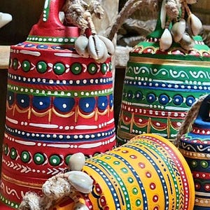 May include: Three colourful ceramic bells with intricate painted designs. Each bell is decorated with a different pattern of red, yellow, green, blue and white. The bells are adorned with white seashells.