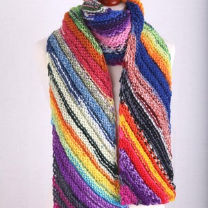Könnte beinhalten: Ein bunter gestreifter Strick Schal mit einem diagonalen Muster. Der Schal ist aus weichem, strukturiertem Garn gefertigt und wird auf einer weißen Puppe präsentiert.