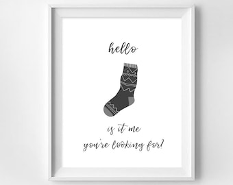 Może przedstawiać: Czarno-biały wydruk artystyczny do druku z tekstem "hello is it me you're looking for?" i czarno-białą ilustracją skarpetki.