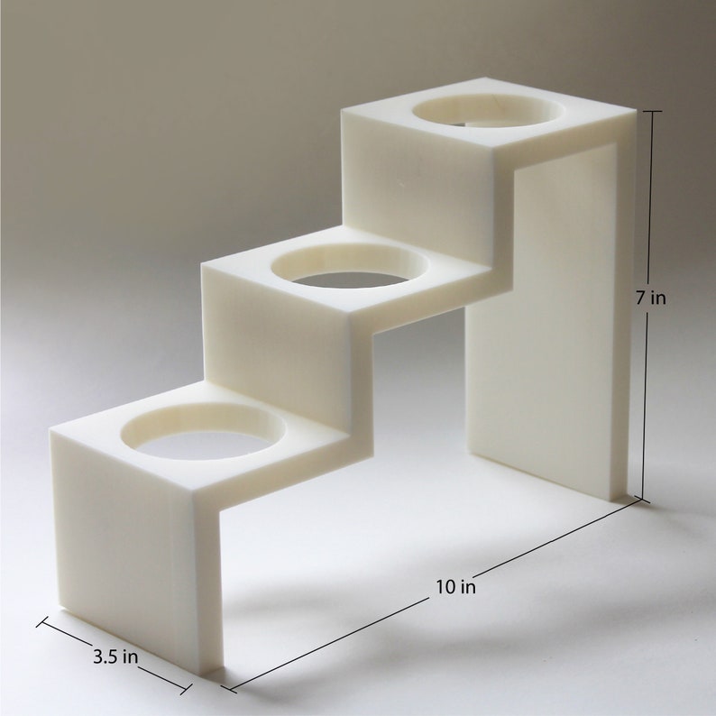 May include: White three-tiered stand with three round openings, measuring 7 inches tall, 10 inches wide, and 3.5 inches deep.
