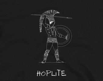 Può includere: T-shirt nera con un'illustrazione bianca di un guerriero oplita greco che tiene una lancia e uno scudo. Il testo "HOPLITE" è stampato sotto l'illustrazione.