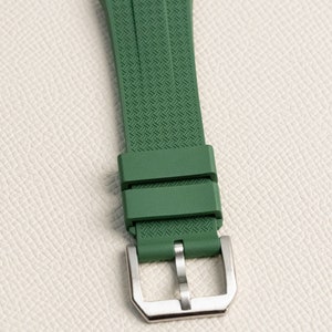 Puede incluir: Una correa de reloj verde con un patr&oacute;n texturizado y una hebilla plateada.