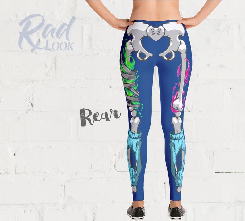 Pode incluir: Leggings azuis com um design de esqueleto com detalhes em verde e rosa. O esqueleto est&aacute; parcialmente quebrado e tem bandagens na perna.