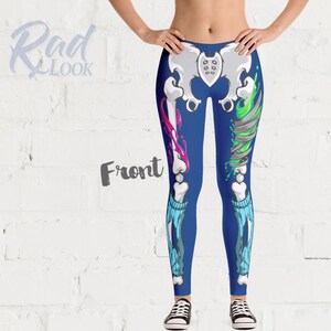 Pode incluir: Leggings azuis com um design de esqueleto com respingos de tinta rosa e verde. As leggings t&ecirc;m um visual rasgado com um padr&atilde;o azul e branco.