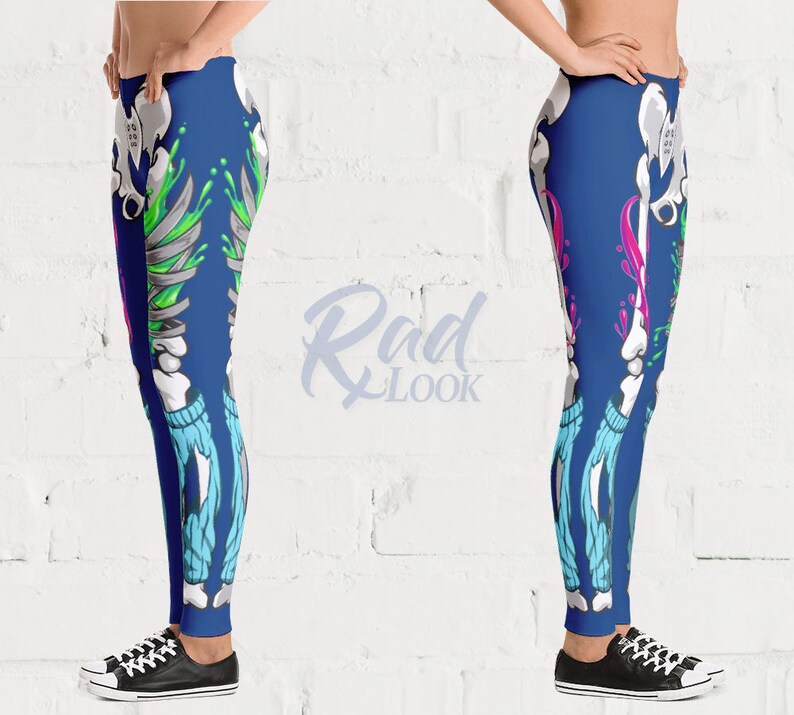Pode incluir: Leggings azuis com um design de esqueleto e respingos de tinta coloridos. O esqueleto est&aacute; vestindo jeans azul.