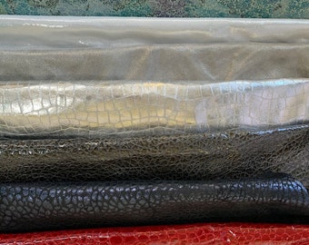 May include: A collection of different colored and textured leather swatches. The swatches are arranged in a stack, with the top swatch being a light beige color and the bottom swatch being a bright red color. The swatches are all different sizes and shapes, and they have a variety of textures, including smooth, embossed, and textured.