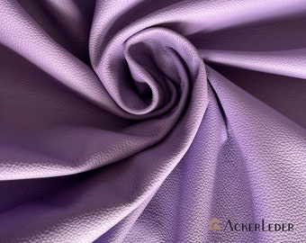 Puede incluir: Primer plano de una tela suave y texturizada de color morado. La tela está doblada y drapeada en un patrón de remolino.
