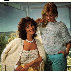 May include: Two women wearing knitted tops. The woman on the left is wearing a white cardigan with a matching white tank top underneath. The woman on the right is wearing a light blue and white sweater. Both women are wearing yellow pants.