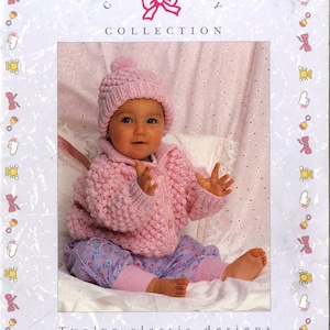 Puede incluir: Un bebé con gorro y chaqueta de punto rosa, combinados con pantalones estampados. La imagen es de la colección Patons Classic Baby, con doce diseños clásicos. El bebé está sentado sobre una superficie blanca.
