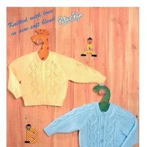 May include: Two knitted baby cardigans, one yellow and one light blue, with a cable knit pattern. The cardigans are hanging on wooden animal hangers. The image includes the text "Peter Pan Double Knit" and "Knitted with love in new soft blend".
