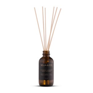 Peut inclure: Un diffuseur à roseaux en verre brun avec une étiquette indiquant "SOJA & CO." et "DIFFUSEUR A ROSEAU REED DIFFUSER". La bouteille contient un liquide et plusieurs roseaux de couleur claire.