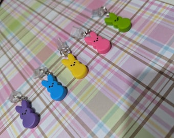 Peut inclure: Six breloques en forme de lapin de différentes couleurs sur un fond blanc. Les breloques sont jaunes, roses, vertes, bleues et violettes. Les breloques sont attachées à des cordons en plastique transparent.
