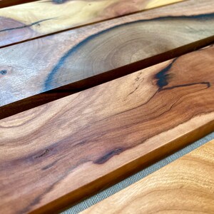 Pu&ograve; includere: Primo piano di una superficie in legno con un motivo a venature del legno naturale. Il legno &egrave; di un colore marrone intenso con venature e nodi pi&ugrave; scuri. La superficie &egrave; liscia e lucida.