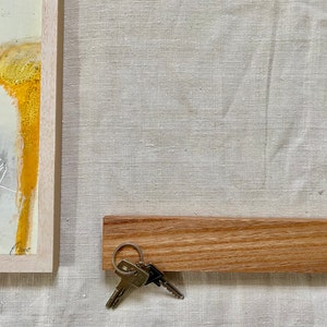 Pu&ograve; includere: Un porta chiavi in legno con un set di chiavi appese. Il porta chiavi &egrave; di colore marrone chiaro e ha una finitura liscia e naturale. Le chiavi sono argentate e hanno un design semplice.