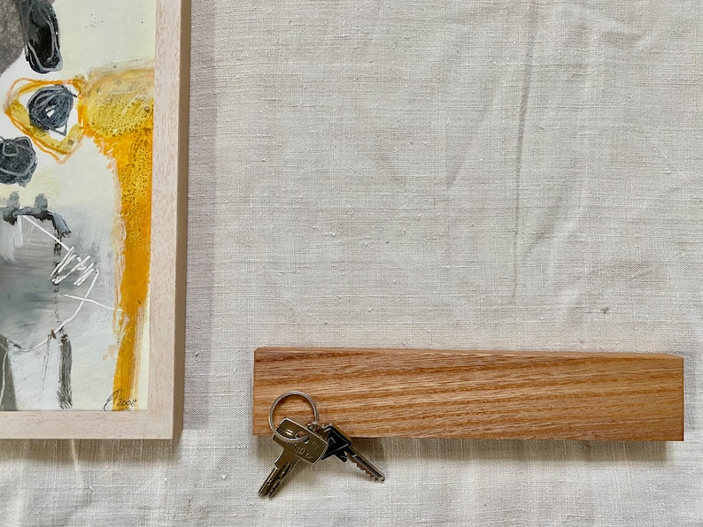 Pu&ograve; includere: Un porta chiavi in legno con un set di chiavi appese. Il porta chiavi &egrave; di colore marrone chiaro e ha una finitura liscia e naturale. Le chiavi sono argentate e hanno un design semplice.