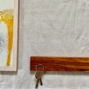 Pu&ograve; includere: Un porta chiavi in legno con una finitura marrone scuro. Un set di chiavi &egrave; appeso a un anello argentato attaccato al porta chiavi.