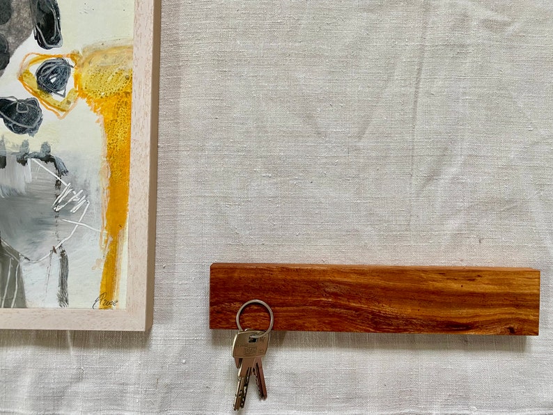 Pu&ograve; includere: Un porta chiavi in legno con una finitura marrone scuro. Un set di chiavi &egrave; appeso a un anello argentato attaccato al porta chiavi.