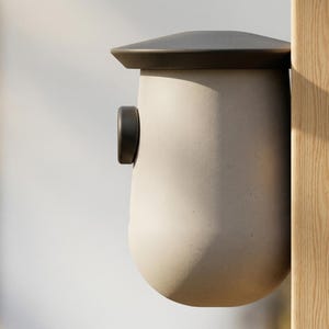 May include: A modern birdhouse with a light gray body and a dark gray roof. The birdhouse is mounted on a natural wood post. A small, dark gray circular detail is on the side.