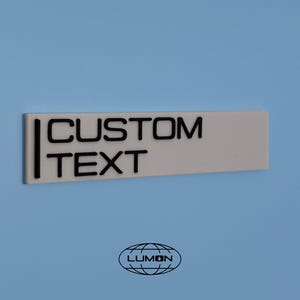 May include: White rectangular sign with black text that reads "CUSTOM TEXT".