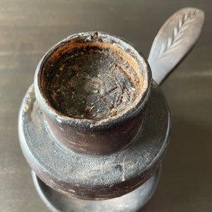 Pu&ograve; includere: Un portacandele in legno marrone scuro con una piccola parte superiore rotonda aperta e una base rotonda separata, pi&ugrave; piccola. Il portacandele ha un manico in legno intagliato con un motivo a foglia.
