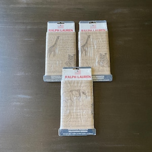 May include: Three packages of Ralph Lauren coordinated decorative wallcovering borders. The packages are tan with illustrations of animals and script. The top of each package has the Ralph Lauren logo.