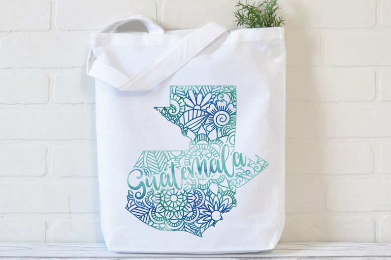 May include: White canvas tote bag with a teal and blue outline of Guatemala with a mandala design and the word "Guatemala" written in a stylized font.