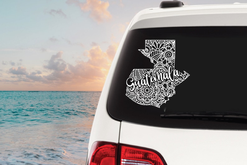 May include: White car decal with a detailed outline of Guatemala and the word "Guatemala" in a stylized font.