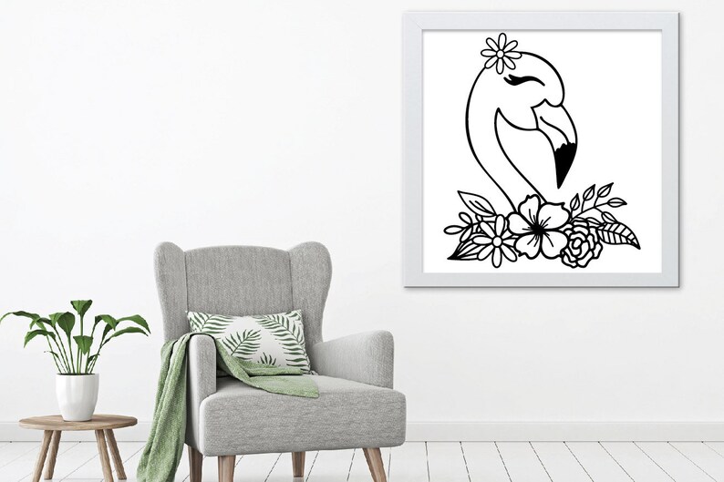 May include: A framed black and white illustration of a flamingo head with a flower crown and floral accents. The artwork is displayed on a white wall above a grey armchair, creating a minimalist aesthetic.