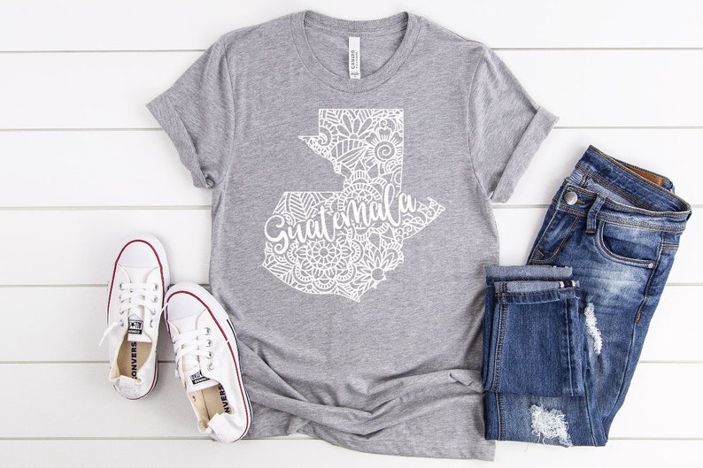 May include: A gray t-shirt with a white outline of Guatemala with a mandala design and the word "Guatemala" written inside the outline.