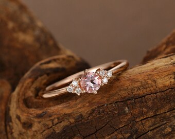May include: A delicate rose gold ring with a pink gemstone surrounded by smaller diamonds.