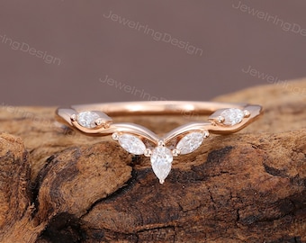 May include: A delicate rose gold wedding band with a V-shaped design featuring five marquise-shaped diamonds.