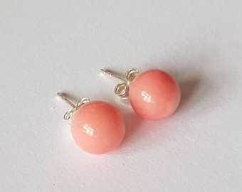 May include: A pair of pink coral stud earrings with silver posts.