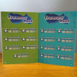 May include: A green and blue book with the title "Treasure Road" on the cover. The book has a list of games with their names and times. The games include "Pop Shots!" "Burst and Rise!" "Throw and Catch!" "Triple Strike!" "Fast and Fiery!" "Freeze and Fling!" "Ready, Aim, Fire!" "Sweet Success!" "Step It Up!" "Hammer Road!" "Dig and Destroy!" "Up and Over!" "Light 'Em Up!" "Slash and Slice!" "Fling, Twirl, Return!"