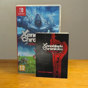 May include: A Nintendo Switch game case and instruction manual for Xenoblade Chronicles: Definitive Edition. The game case features a blue and white background with a large, mechanical creature in the background. The instruction manual is black with red accents and the game title.