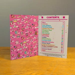 May include: A pink and white booklet with the title "CONTENTS" and a list of game features for the video game Kirby and the Forgotten Land. The cover of the booklet features a pink background with a pattern of Kirby characters.