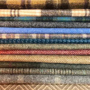 May include: A stack of 14 different patterned fabric swatches. The swatches are rolled and stacked on top of each other. The fabrics are a variety of colours, including brown, beige, blue, green, and red.