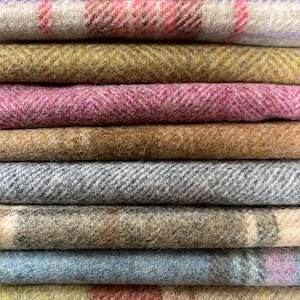 May include: A stack of colourful fabric swatches with different patterns, including plaid, herringbone, and stripes. The swatches are made of a soft, textured material.