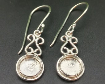 Op de afbeelding: Een paar zilveren oorbellen met een delicaat filigraan ontwerp en een ronde bezel-setting. De oorbellen zijn perfect om een ​​toets van elegantie toe te voegen aan elke outfit.