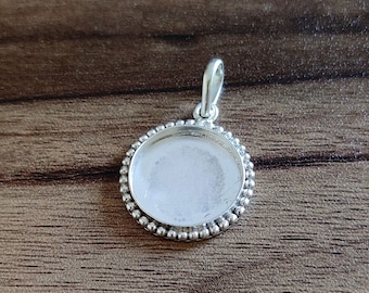 May include: Silver pendant with a round, smooth, beveled edge and a beaded border. The pendant has a loop at the top for attaching a chain.