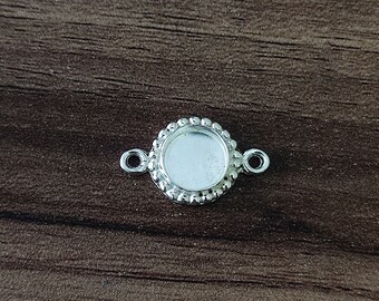 May include: Silver-toned round pendant with a bezel setting and two jump rings. The pendant has a beaded edge.