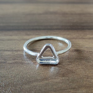 Puede incluir: Un anillo de plata con un corte en forma de triángulo en el centro.