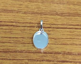 Può includere: Ciondolo in argento con una superficie rotonda, liscia e vuota. Il ciondolo ha un anello nella parte superiore per attaccarlo a una catena.