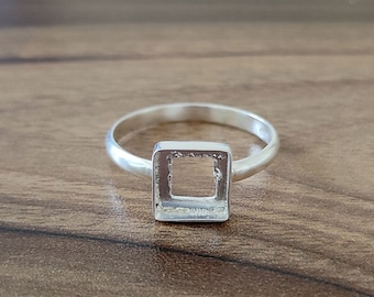 May include: A silver ring with a square-shaped cutout in the center.