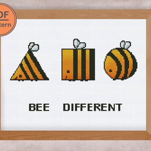 May include: A cross-stitch pattern featuring three bees in different shapes, with the text "BEE DIFFERENT" below. The bees are yellow and black with a pixelated design.