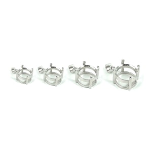 May include: Four silver pendant settings with round bezels, each with a different size. The bezels have a cage-like design with vertical bars.