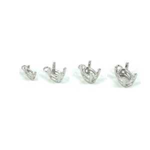 May include: Four silver-coloured oval-shaped jewellery settings are displayed against a white background. Each setting has four prongs to hold a gemstone. The settings vary in size, with the smallest on the left and the largest on the right.