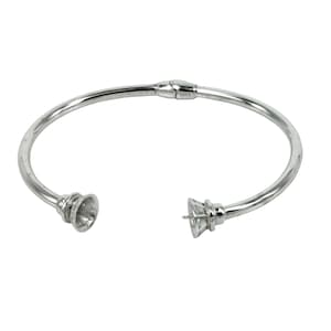 May include: Silver bangle bracelet with a hinged opening and a decorative end cap. The end cap is a cone shape with a small hole in the center.