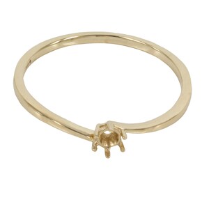 May include: A gold ring with a prong setting for a gemstone. The ring is simple and delicate, with a smooth band.